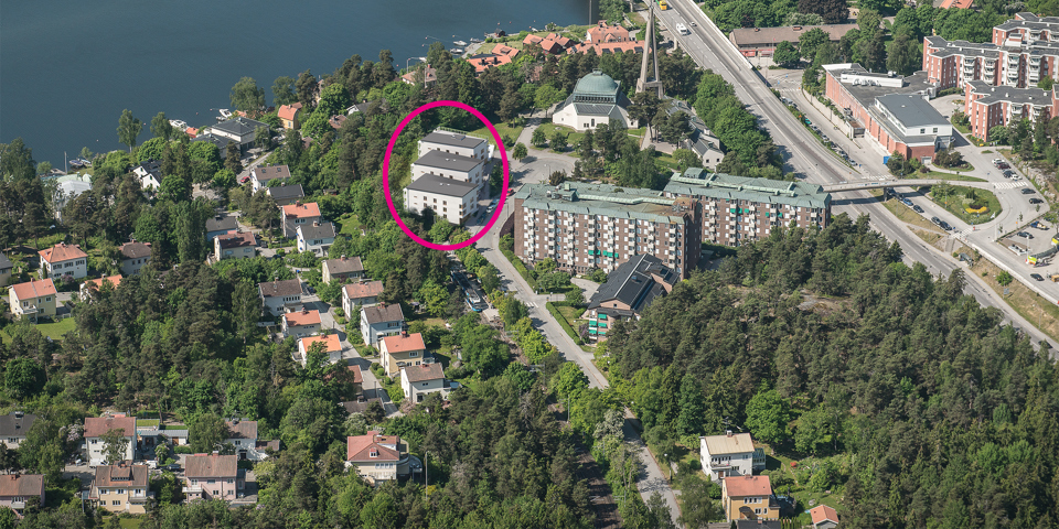 Flygbild över Nockeby med bostadshus, grönområden och Nockebybron. Tre bostadshus markerade i en röd cirkel. Illustration/foto